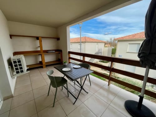 Balcone dello studio a Résidence Marina di Bravone con tavolo da pranzo, sedie e vista sugli appartamenti vicini a Linguizzetta