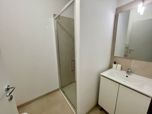 Bagno moderno presso la Résidence Marina di Bravone a Linguizzetta con vanity bianco, specchio e doccia in cristallo