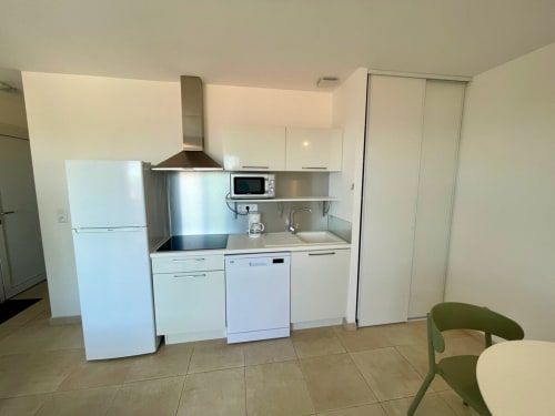 Moderna cucinetta presso Résidence Marina di Bravone con elettrodomestici bianchi, piano cottura e lavello in acciaio inox a Linguizzetta