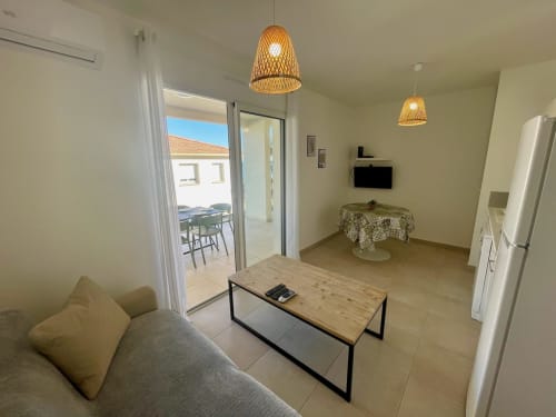 Appartement moderne à la Résidence Marina di Bravone avec vue sur mer, séjour ouvert, luminaires suspendus tissés et accès à la terrasse