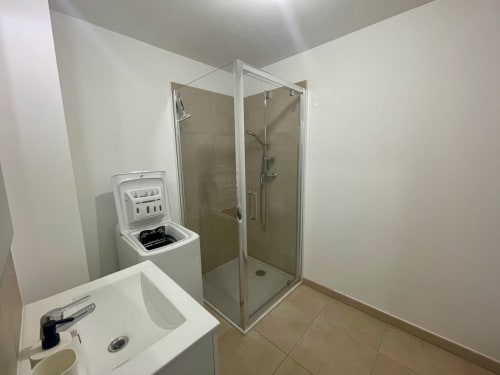 Salle de bain moderne à la Résidence Marina di Bravone avec lavabo, toilettes, lave-linge et douche vitrée