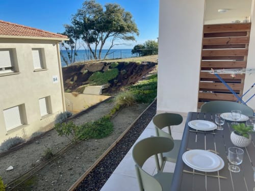Patio avec vue mer de l'appartement en front de mer de Marina di Bravone, table à manger et paysage côtier à Linguizzetta