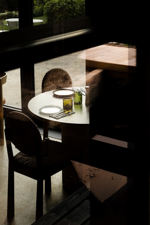 Coin repas intimiste au gîte Moulin Moulin à Dannes avec table ronde blanche, couverts et chaises en osier baignées de lumière naturelle
