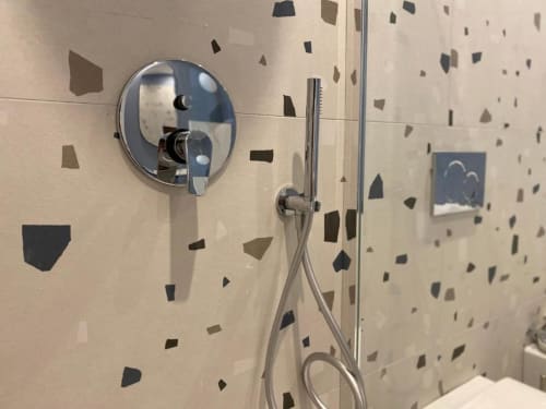 Doccia moderna nella parete del bagno dell'appartamento Mas Collection Bari con specchio rotondo e soffione manuale