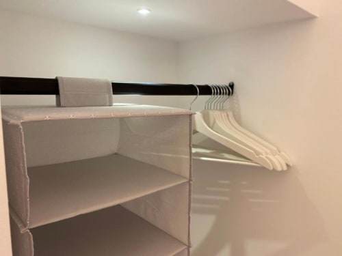 Armadio con asta nera, organizer bianco e grucce color crema nell'Appartamento Superior Mas Collection, Bari