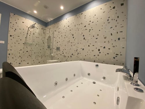 Lussuoso bagno moderno con vasca idromassaggio e rivestimenti in terrazzo presso l'Apartment Superior di Mas Collection, Bari
