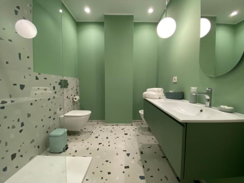 Bagno moderno dell'appartamento Mas Collection Bari con pareti verdi, pavimento in terrazzo, doccia walk-in e lampada a sospensione rotonda