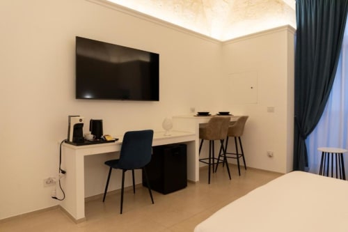 Camera moderna di Mas Collection a Bari con scrivania da lavoro, TV a parete e elegante zona salotto