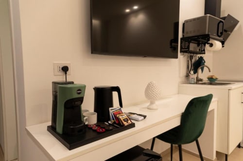 Angolo cottura moderno nella Mas Collection Bari con caffettiera, bollitore nero e sedia verde alla scrivania bianca