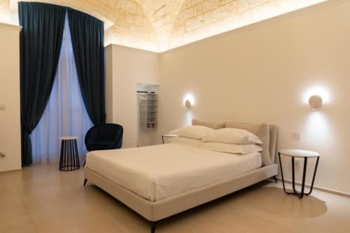 Modern beige bedroom in Mas Collection Bari with cream bed, black curtains, and ambient wall lighting