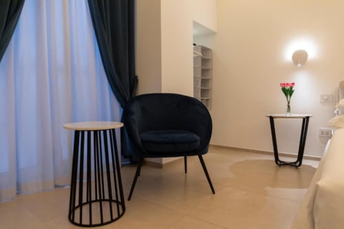 Zona living moderna dell'Appartamento Superior di Mas Collection a Bari, con poltrona nera, tavolino in legno e tocchi di rosa