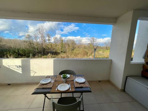 Beachfront apartment balcony at Résidence Marina di Bravone with dining table overlooking wetlands and blue sky