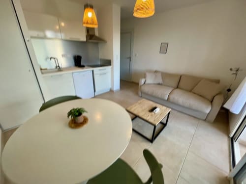 Modern T2 apartment at Marina di Bravone, Linguizzetta featuring living area with sofa, dining table, and equipped kitchen