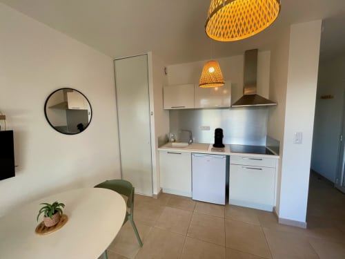 Modern kitchenette with white cabinets and stainless steel backsplash in cosy beachfront apartment at Marina di Bravone,