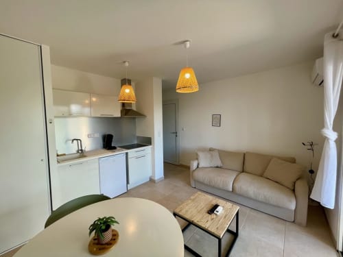 Cosy beachfront T2 apartment at Marina di Bravone with open-plan living, white kitchen, dining table, sofa and pendant lights