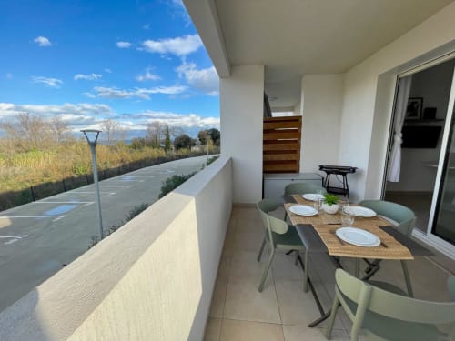 Modern apartment balcony with dining table overlooking countryside near Linguizzetta, Corsica