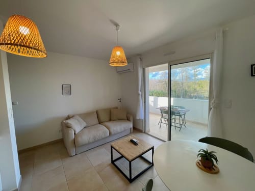 Modern apartment living room at Marina di Bravone with beige sofa, woven pendant lights, and balcony views
