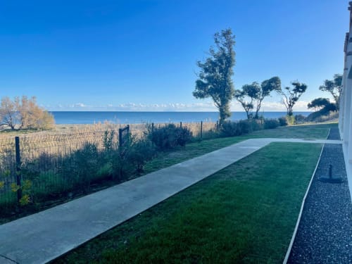Résidence Marina di Bravone beachfront apartment patio with sea view, lawn and pathway in Linguizzetta, France