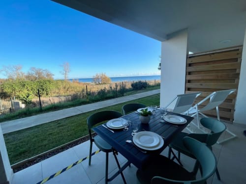 Modern terrace at Marina di Bravone with dining table, lounge chairs, sea view, and beach access in Linguizzetta, France