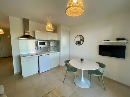 Modern T2 apartment at Résidence Marina di Bravone with open-plan kitchen, dining area, and flat-screen TV in Linguizzetta