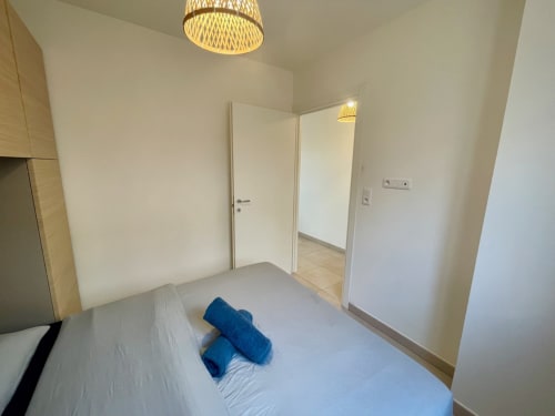 Bedroom at Résidence Marina di Bravone with bed, blue pillows, and open doorway to living area