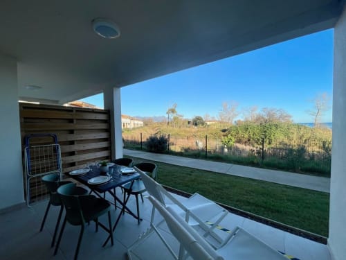 Modern patio at Résidence Marina di Bravone with dining table, sea view, and coastal landscape in Linguizzetta