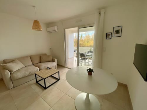 Accogliente appartamento moderno a Marina di Bravone con divano beige, tavolo da pranzo bianco e balcone vista mare