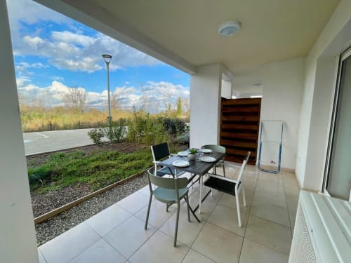 Patio coperto della Résidence Marina di Bravone con tavolo da pranzo, vista sulle montagne e giardino paesaggistico a Linguizzetta