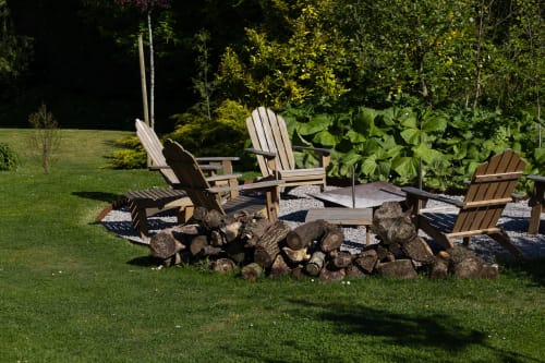 Chaises Adirondack autour d'un foyer au Moulin Moulin B&B à Dannes, France, avec pelouse soignée et verdure luxuriante