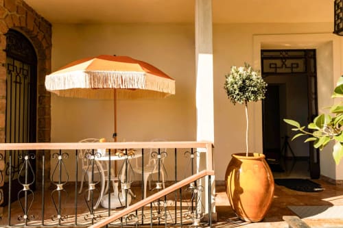 Ombrellone arancione con frangia sulla terrazza dell'Hôtel Villa Martini Ajaccio con balaustra ornamentale e pianta topiaria