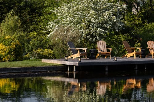 Chaises Adirondack en bois sur la terrasse du Moulin Moulin B&B à Dannes, vue sur l'eau calme et les jardins fleuris