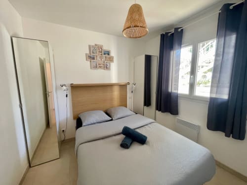 Camera da letto accogliente a Résidence Marina di Bravone, Linguizzetta con letto in legno, specchio e lampadario in vimini