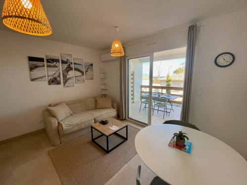Accogliente appartamento a Résidence Marina di Bravone con divano beige, arredamento moderno e vista dal balcone