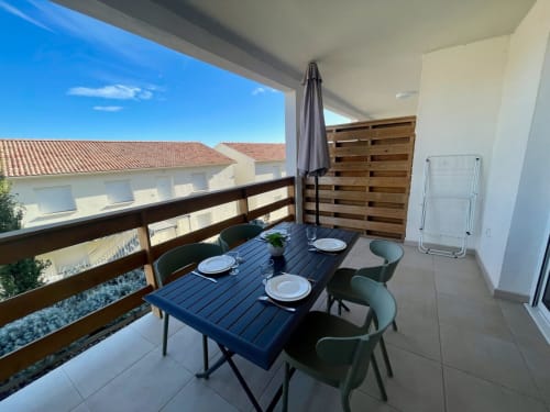 Balcone luminoso della Résidence Marina di Bravone con tavolo da pranzo, vista mare e schermo privacy in legno