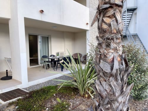 Elegante terrazza moderna della Résidence Marina di Bravone con tavolo da pranzo, palma in vaso e vista costiera della Corsica
