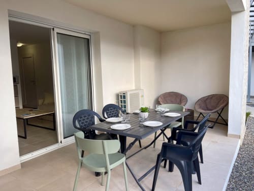 Moderna zona pranzo in terrazza dell'appartamento Marina di Bravone con tavolo apparecchiato, sedute contemporanee e vetrate scorrevoli