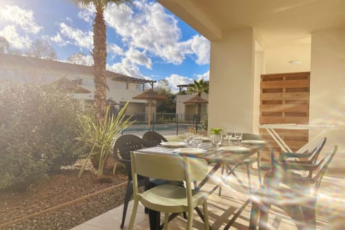 Terrazza pranzo della Résidence Marina di Bravone con tavolo, sedie, palma e vista mare a Linguizzetta