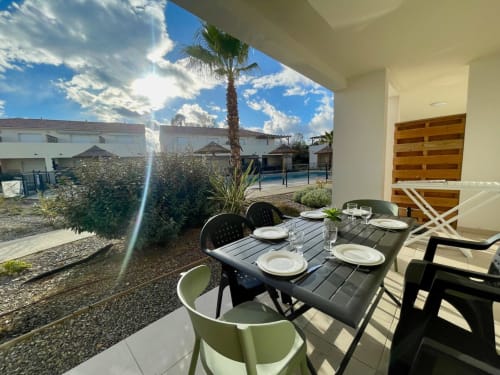 Terrazza pranzo all'aperto della Résidence Marina di Bravone con tavolo apparecchiato, palma e vista piscina a Linguizzetta
