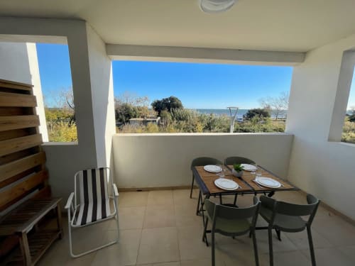 Marina di Bravone beachfront apartment terrace with dining table, sea view, and landscaped grounds in Linguizzetta