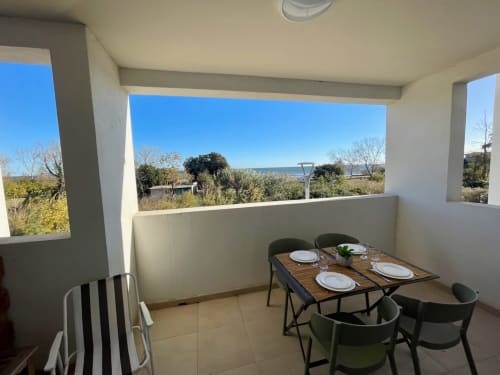 Beachfront apartment balcony at Marina di Bravone with dining table, sea view, and Mediterranean landscape in Linguizzetta