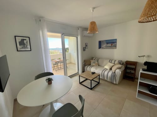 Marina di Bravone apartment T2 with sea view, dining area, sofa, and balcony access in Linguizzetta
