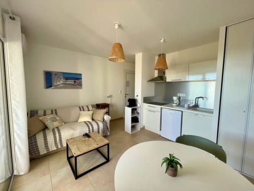 Modern T2 apartment at Résidence Marina di Bravone in Linguizzetta with open kitchen, sofa, dining table, and woven pendant