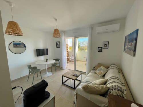 Modern apartment at Marina di Bravone with sea view balcony, living area, sofa, dining table and woven pendant lights