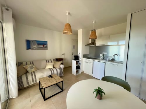 Modern studio apartment at Résidence Marina di Bravone with sofa, kitchen, dining table, and woven pendant lights