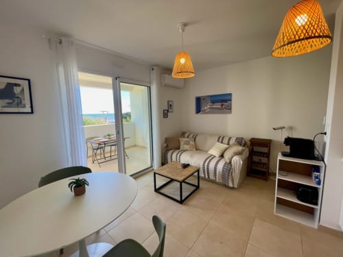 Modern T2 apartment at Résidence Marina di Bravone with sea view terrace, dining area, and striped sofa in Linguizzetta