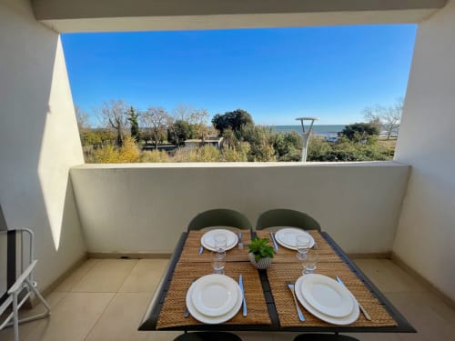Beachfront apartment balcony at Marina di Bravone with sea view, dining table set for four, and coastal landscape