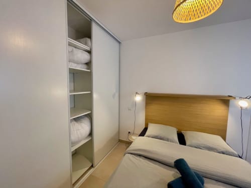 Cozy bedroom at Résidence Marina di Bravone with wood headboard, built-in wardrobe, and yellow ceiling lamp in Linguizzetta