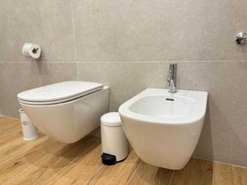 Bagno moderno con toilette a parete, bidet e lavabo bianchi presso l'appartamento Mas Collection a Bari