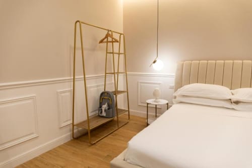 Camera da letto moderna beige Mas Collection Bari, con appendiabiti in ottone, testiera color crema e pavimento in legno