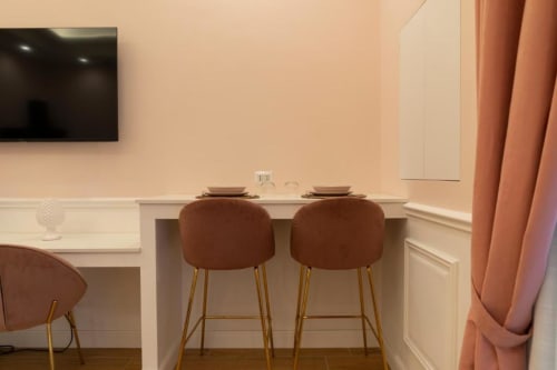 Studio moderno con due sgabelli in terracotta della Collezione Mas nell'appartamento di Bari, con TV e tende color corallo
